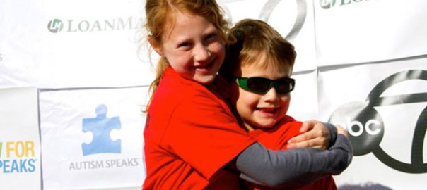 sister and brother hugging and smiling at autism event
