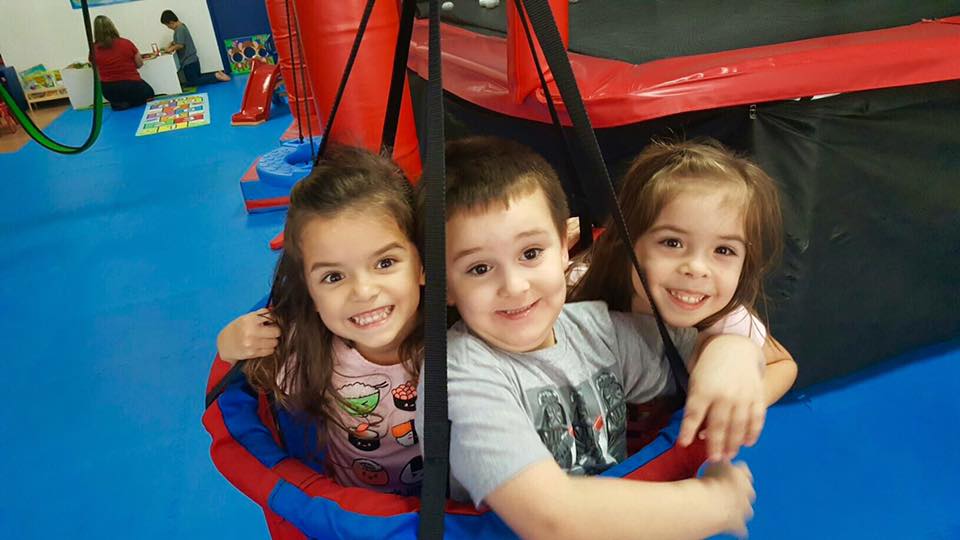 3 children sitting in swing together